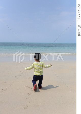 A boy about two years old was wearing a long-sleeved shirt standing on the beach. 117746028