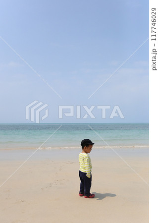 A boy about two years old was wearing a long-sleeved shirt standing on the beach. A boy about two years old was wearing a long-sleeved shirt standing on the beach. 117746029
