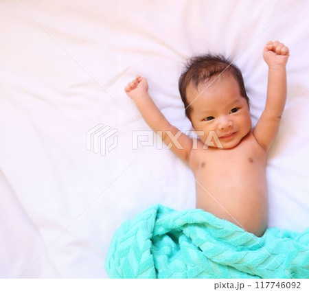 Infant boy lies clenched on a white mattress. Infant boy lies clenched on a white mattress. 117746092