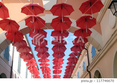 Lots of red umbrellas flying in sky over city street  in Venice, Italy 117746670