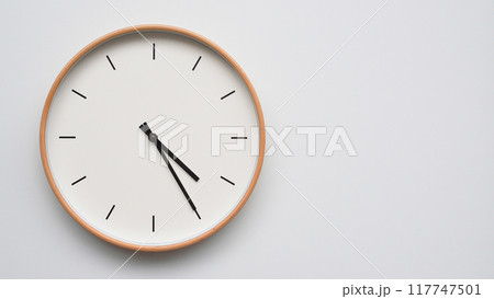 Minimalist wooden Wall Clock on White Wooden Surface with Space for Text. Time Set at 16.25/04.25 117747501