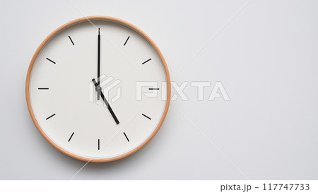 Minimalist wooden Wall Clock on White Wooden Surface with Space for Text. Time Set at 17.00/05.00 117747733