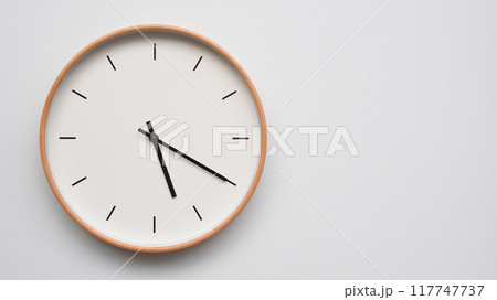 Minimalist wooden Wall Clock on White Wooden Surface with Space for Text. Time Set at 17.20/05.20 117747737