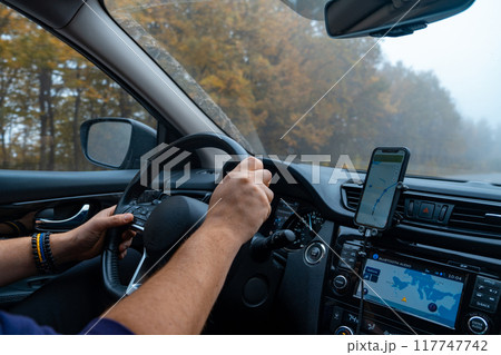 Person Driving by the road at foggy autumn highway Person Driving by the road at foggy autumn highway 117747742