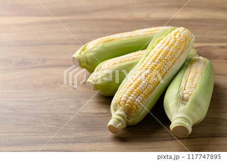 Fresh sweet corn (bicolor) on wooden background Fresh sweet corn (bicolor) on wooden background 117747895
