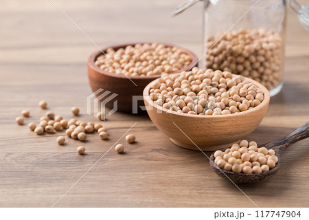 Soy bean seeds in wooden bowl, glass jar and spoon on wooden background Soy bean seeds in wooden bowl, glass jar and spoon on wooden background 117747904