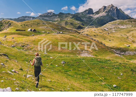 Woman Hiker Traveling in Mountains with High Peaks Woman Hiker Traveling in Mountains with High Peaks 117747999