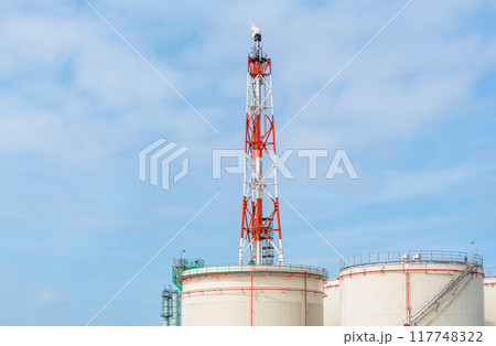 大型石油タンクとフレアスタック（火炎）を上げる鉄塔 117748322