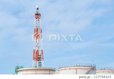 大型石油タンクとフレアスタック（火炎）を上げる鉄塔 117748323