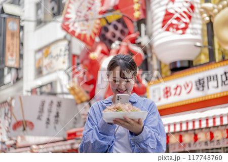 スマホでたこ焼きを撮っている若い女性 117748760