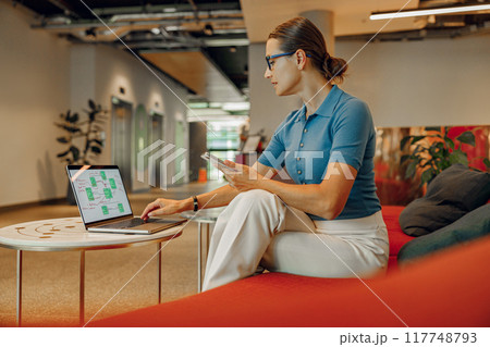 A Business Professional is Working Remotely in a Modern Office Space with Great Vibes A Business Professional is Working Remotely in a Modern Office Space with Great Vibes 117748793