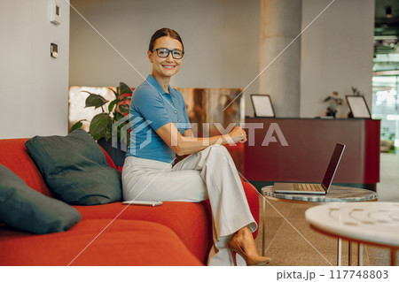 A Confident Businesswoman Smiling Happily in a Modern Office Setting with Stylish Decor 117748803
