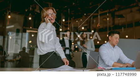 A Busy Professional Team Collaboratively Working Together in a Modern Office Environment A Busy Professional Team Collaboratively Working Together in a Modern Office Environment 117748990