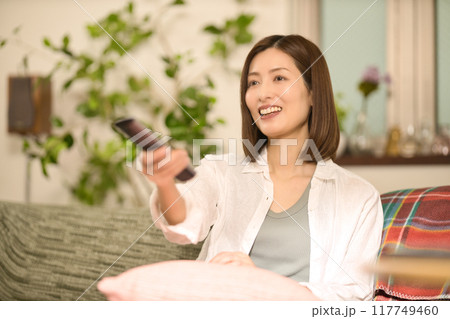 ソファでくつろぎながらテレビを見るミドル女性 117749460