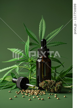 CBD Oil Bottle with Hemp Seeds, Cannabis Leaves and bud on Green Background 117750899
