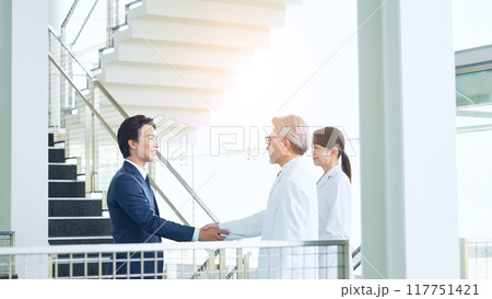 白衣の技術者と握手するビジネスマン 117751421