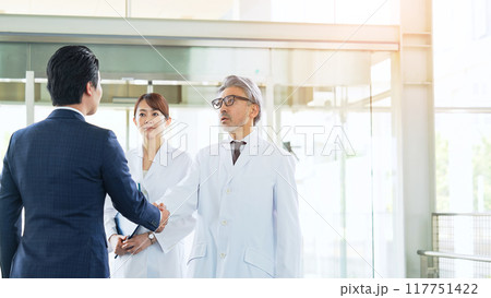 白衣の技術者と握手するビジネスマン 117751422