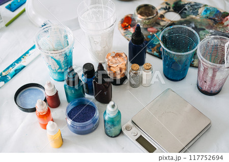 Colorful resin pigments and tools on a worktable, DIY art supplies, creative studio setup, epoxy resin project, artist workspace, crafting materials, vibrant color palette Colorful resin pigments and tools on a worktable, DIY art supplies, creative studio setup, epoxy resin project, artist workspace, crafting materials, vibrant color palette 117752694