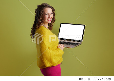 smiling woman showing laptop blank screen isolated on green 117752786