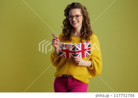 smiling fit woman in sweater and glasses against green 117752788