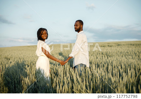 Outdoor shot of young couple walking through meadow hand in hand. African american ethnicity marriage walk through grass field in countryside. Outdoor shot of young couple walking through meadow hand in hand. African american ethnicity marriage walk through grass field in countryside. 117752798