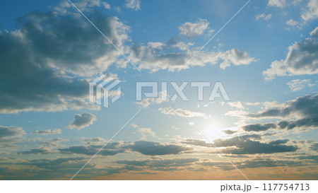 Sun below the horizon and clouds in the fiery dramatic sky. Clouds illuminated by sunbeams. Timelapse. Sun below the horizon and clouds in the fiery dramatic sky. Clouds illuminated by sunbeams. Timelapse. 117754713