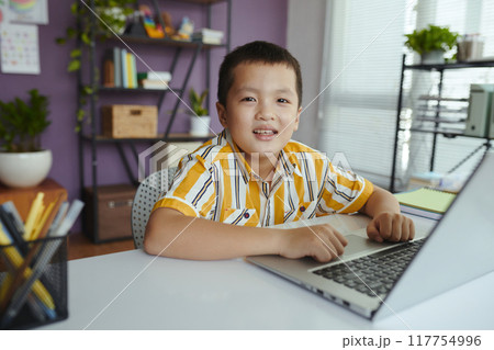 Portrait of Smiling Boy Sitting with Laptop at Desk Portrait of Smiling Boy Sitting with Laptop at Desk 117754996