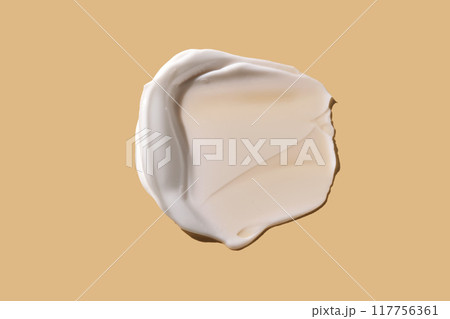 A smear of white cream on a beige background. 117756361