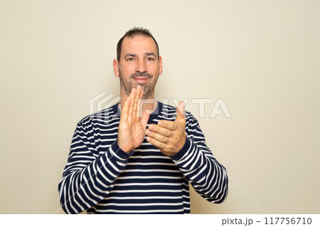 Bearded hispanic man about 40 years old isolated over beige background applauding after his presentation at a conference Bearded hispanic man about 40 years old isolated over beige background applauding after his presentation at a conference 117756710