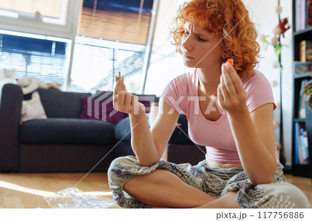 teenage girl assembles construction set according to instructions sitting on floor in room 117756886
