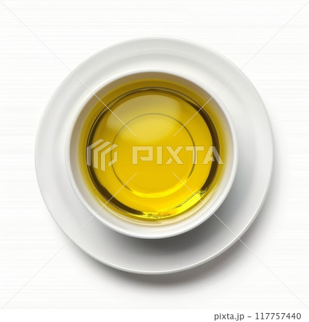 Top view of a bowl of clear yellow liquid, possibly oil or broth, on a white surface. Top view of a bowl of clear yellow liquid, possibly oil or broth, on a white surface. 117757440
