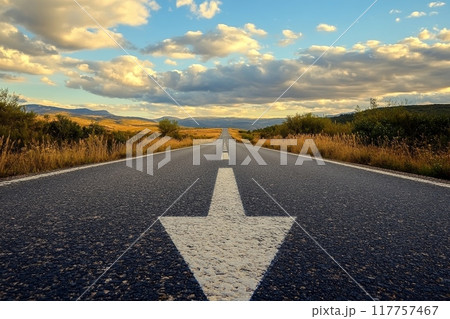 A long stretch of road leading to distant mountains, bathed in warm sunset light with dramatic clouds overhead A long stretch of road leading to distant mountains, bathed in warm sunset light with dramatic clouds overhead 117757467