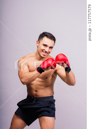 Confident male boxer in red gloves prepares for intense fight in studio 117757579