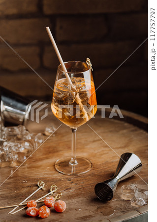Elegant cocktail on a rustic wooden table with garnishes and ice, perfect for upscale bars 117757797
