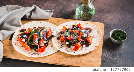 Delicious tacos with fried mushrooms, tomatoes, onions and feta on a board web banner 117757903