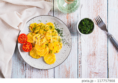 Appetizing grilled potatoes with tomatoes and dill on a plate on the table top view Appetizing grilled potatoes with tomatoes and dill on a plate on the table top view 117757908