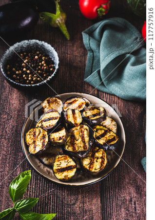 Delicious pieces of grilled eggplant on a plate on the table vertical view Delicious pieces of grilled eggplant on a plate on the table vertical view 117757916