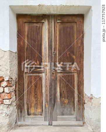 Old wooden damaged brown door of brick building 117757928