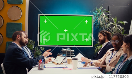 Marketing team meeting in a boardroom with isolated TV display, working together to improve the organization public image and social media presence. Business specialists conduct analysis. Camera B. 117758806