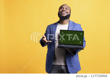 Portrait of relaxed carefree man pointing towards green screen laptop, doing endorsement. Delighted tech reviewer giving positive feedback to chroma key notebook, isolated over studio background Portrait of relaxed carefree man pointing towards green screen laptop, doing endorsement. Delighted tech reviewer giving positive feedback to chroma key notebook, isolated over studio background 117758908