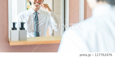 朝出勤前に洗面所で歯を磨くスーツ姿の若いアジア人男性（口腔ケア・オーラルケア） 117762876