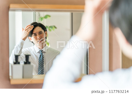 洗面所で頭皮の生え際を機にする若いアジア人男性(薄毛・脱毛・AGA・抜け毛) 洗面所で頭皮の生え際を機にする若いアジア人男性(薄毛・脱毛・AGA・抜け毛) 117763214