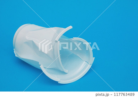 White plastic damaged drink glass on blue background. 117763489