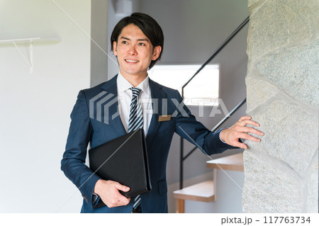 レンガの内壁材の説明をするハウスメーカーのアドバイザー・プランナーの男性 レンガの内壁材の説明をするハウスメーカーのアドバイザー・プランナーの男性 117763734