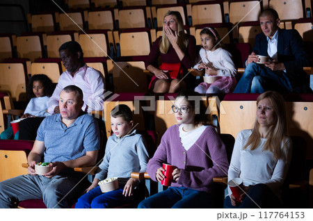 Scared and shocked adults and children watching movie in cinema 117764153