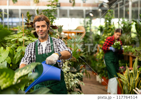 Professional man florist withe plastic watering can in shop 117764514