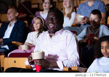 caucasian mother, african father and their children sitting at comedy in auditorium caucasian mother, african father and their children sitting at comedy in auditorium 117764520