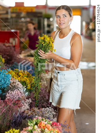 Girl customer in flower shop chooses dry flowers to form ikebana 117764624