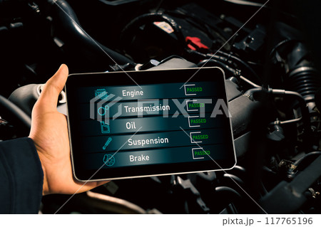 Mechanic checks car maintenance with wireless scan tool with car engine compartment background. 117765196