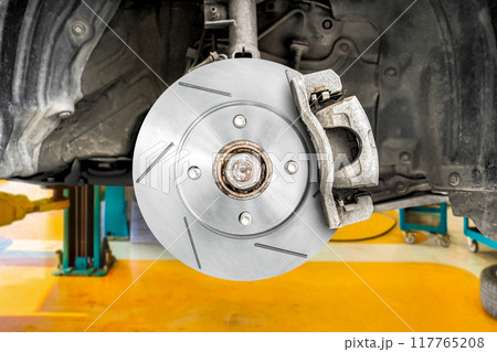 Install new slotted brake rotors on the car in the auto repair center Install new slotted brake rotors on the car in the auto repair center 117765208
